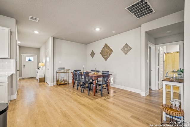 dining area featuring a textured ceiling and light hardwood / wood-style flooring