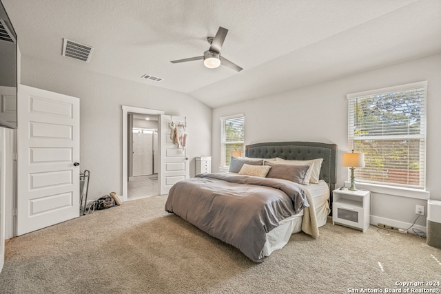 bedroom with vaulted ceiling, ceiling fan, multiple windows, and carpet flooring