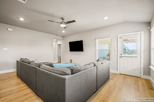 living room with ceiling fan, a textured ceiling, light hardwood / wood-style flooring, and lofted ceiling