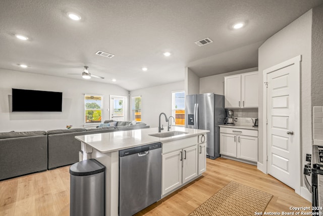 kitchen with white cabinets, lofted ceiling, a center island with sink, appliances with stainless steel finishes, and light hardwood / wood-style floors