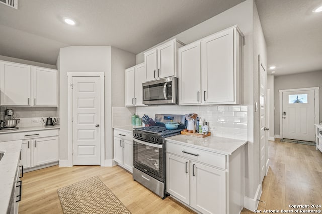 kitchen featuring appliances with stainless steel finishes, decorative backsplash, light hardwood / wood-style floors, and white cabinetry