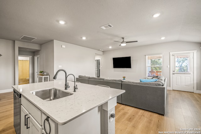 kitchen featuring light hardwood / wood-style floors, sink, white cabinets, lofted ceiling, and a center island with sink