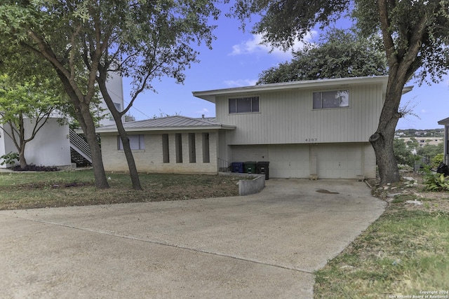 4207 High Sierra, San Antonio, TX 78228 - rear view of property with an attached garage, concrete driveway, brick siding, and metal roof