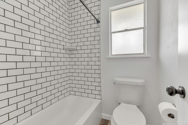 bathroom with tiled shower / bath combo and toilet