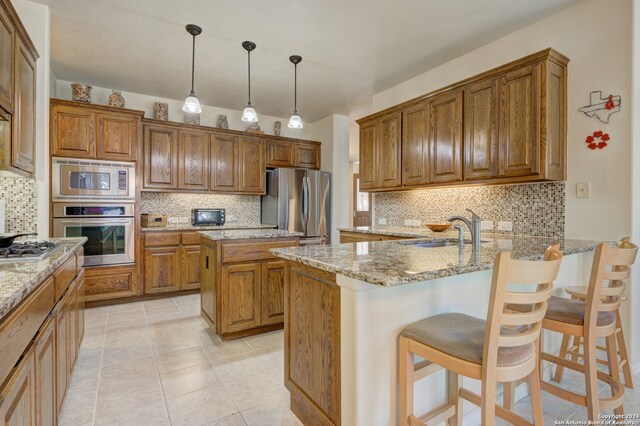 kitchen featuring a breakfast bar, sink, a kitchen island, decorative backsplash, and stainless steel appliances