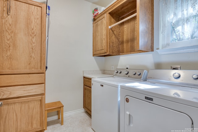 laundry room with washing machine and dryer, light tile patterned flooring, and cabinets