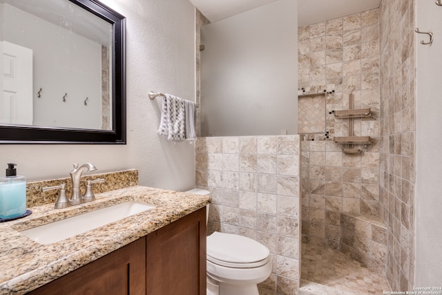 bathroom with tiled shower, vanity, and toilet