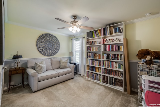 sitting room with ceiling fan, light colored carpet, and crown molding