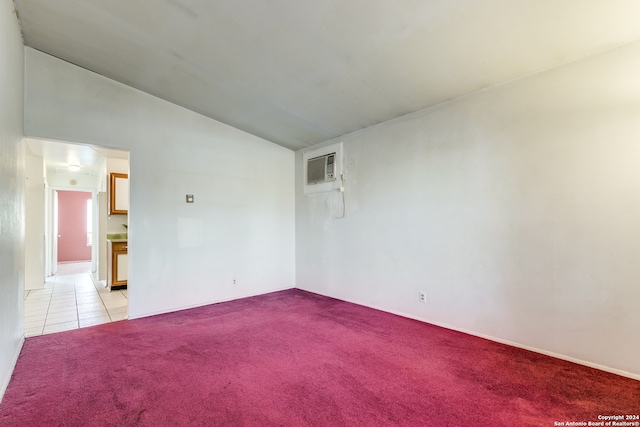 unfurnished room with vaulted ceiling, a wall mounted AC, and light colored carpet