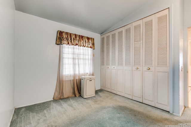 unfurnished bedroom with lofted ceiling, a closet, and light colored carpet