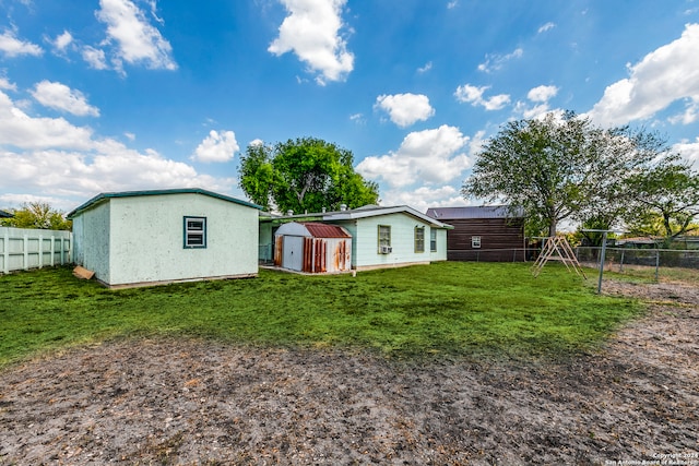 rear view of property featuring a shed, a playground, and a yard