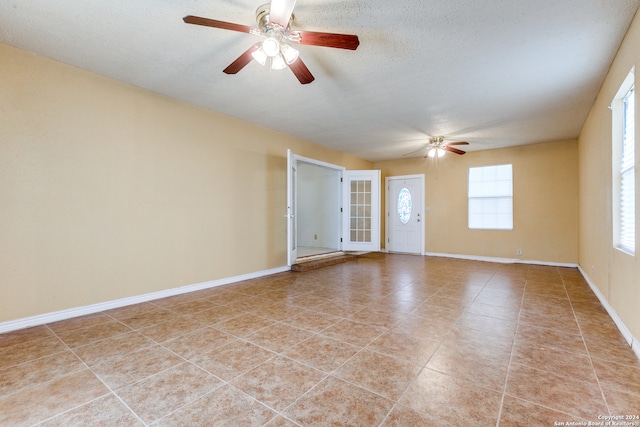 spare room featuring a textured ceiling, ceiling fan, and light tile patterned floors