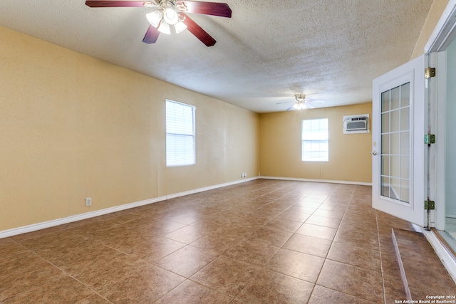 unfurnished room featuring a textured ceiling, ceiling fan, a wall mounted AC, and plenty of natural light