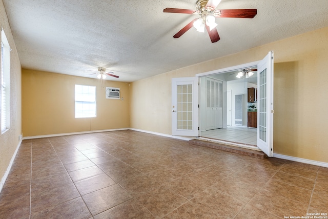 tiled empty room with ceiling fan, a textured ceiling, and a wall mounted AC