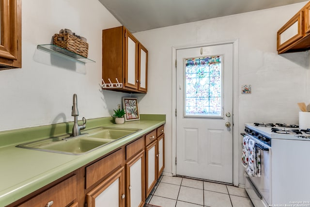 kitchen with white gas stove, light tile patterned floors, and sink