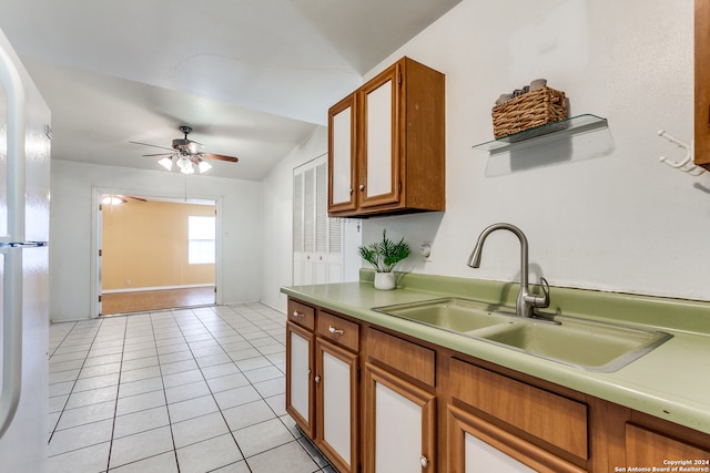 kitchen with ceiling fan, white refrigerator, light tile patterned floors, sink, and vaulted ceiling