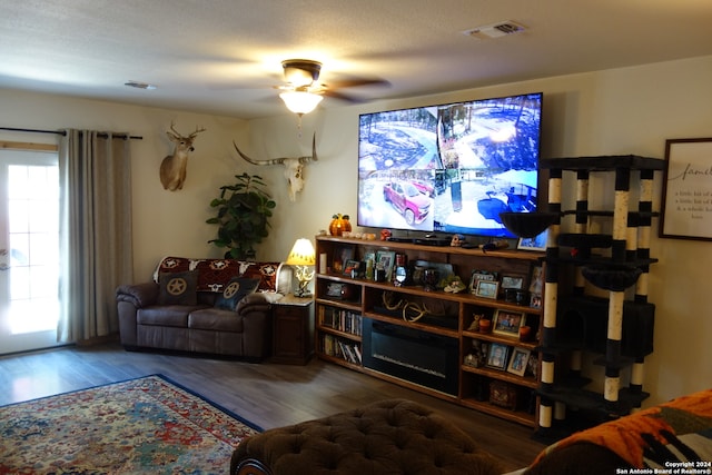 living room featuring a textured ceiling, ceiling fan, and dark hardwood / wood-style flooring