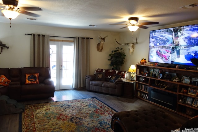 living room with a textured ceiling, wood-type flooring, and ceiling fan