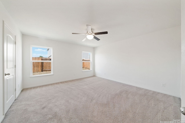 empty room with a wealth of natural light, ceiling fan, and light colored carpet