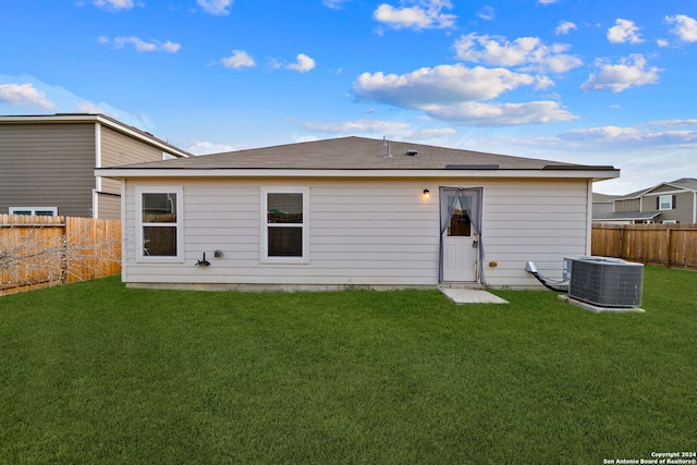 back of house featuring a lawn and central air condition unit