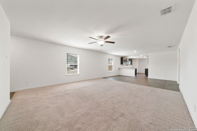 unfurnished living room featuring ceiling fan and dark carpet