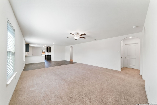 unfurnished living room with dark carpet and ceiling fan