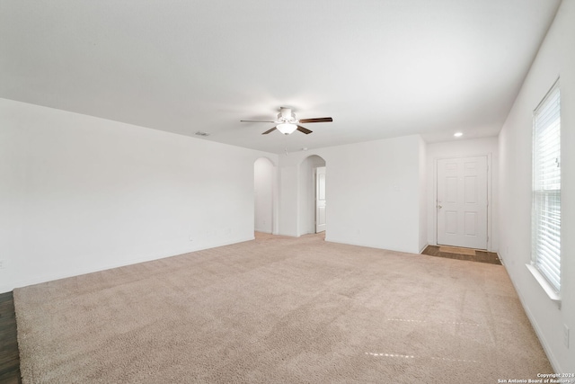 carpeted spare room featuring ceiling fan and plenty of natural light