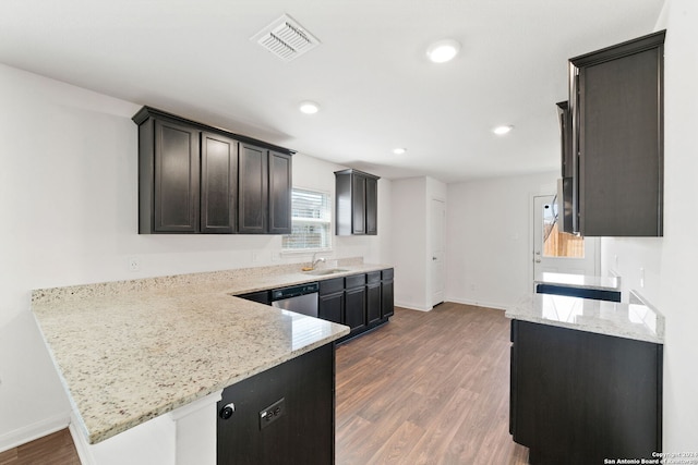 kitchen with stainless steel dishwasher, sink, dark wood-type flooring, and light stone counters