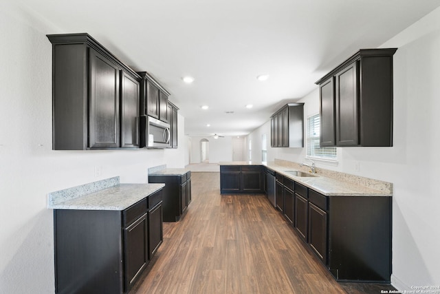 kitchen featuring appliances with stainless steel finishes, kitchen peninsula, ceiling fan, dark hardwood / wood-style floors, and sink