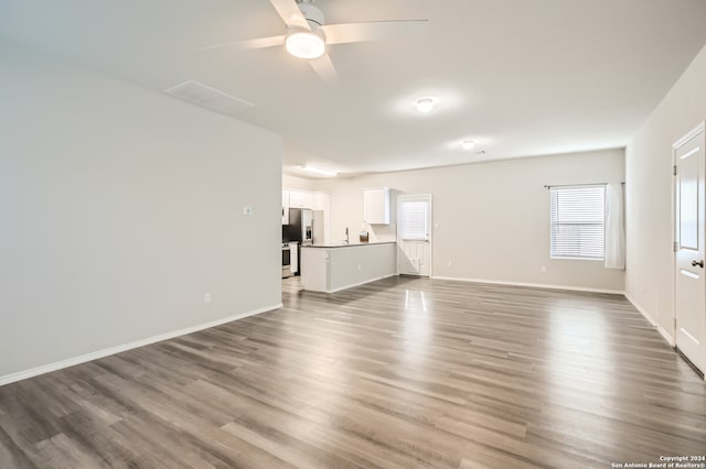 unfurnished living room featuring dark hardwood / wood-style floors, ceiling fan, and sink