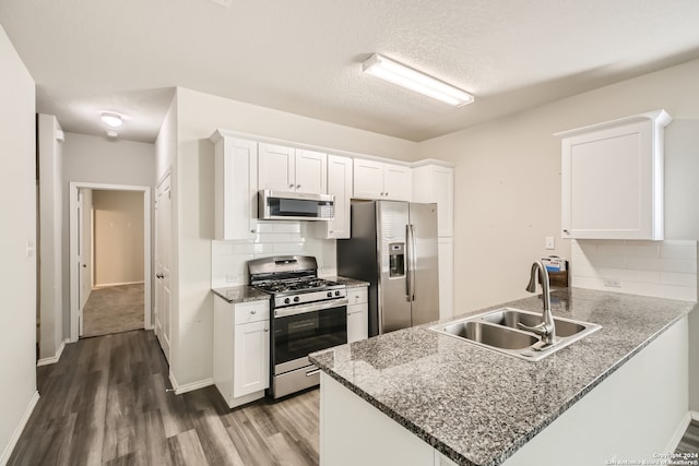 kitchen featuring sink, kitchen peninsula, white cabinetry, stainless steel appliances, and dark hardwood / wood-style flooring