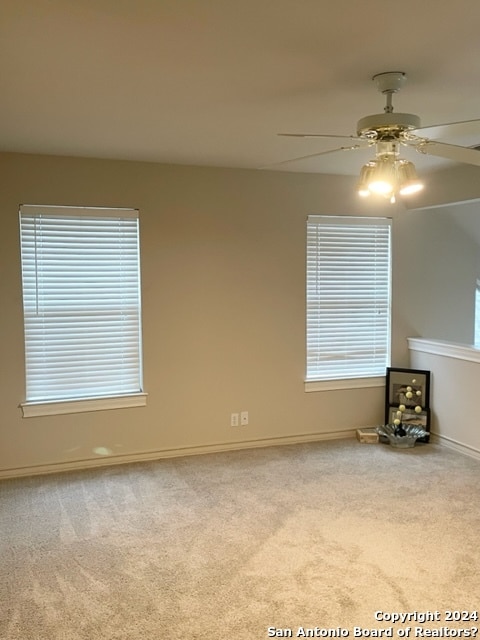 unfurnished living room featuring ceiling fan and light colored carpet