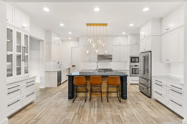 kitchen with a kitchen island with sink, appliances with stainless steel finishes, light hardwood / wood-style floors, and white cabinetry