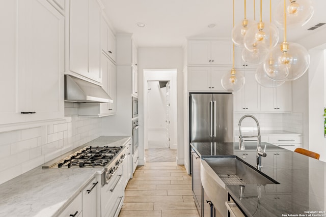 kitchen featuring light stone counters, exhaust hood, decorative light fixtures, and white cabinetry