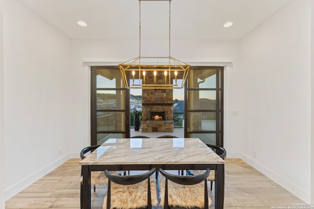 dining area with a fireplace, hardwood / wood-style floors, and a chandelier