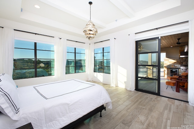 bedroom with light hardwood / wood-style flooring, a chandelier, and a raised ceiling