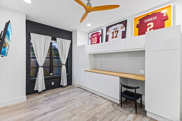 home office with ceiling fan, built in desk, and light hardwood / wood-style floors