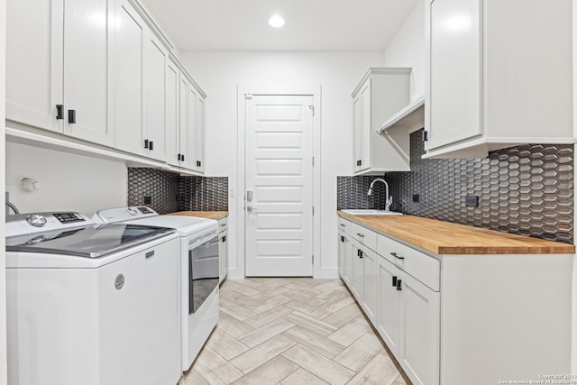 washroom with cabinets, independent washer and dryer, and sink