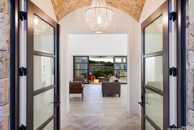 entrance foyer featuring lofted ceiling, a chandelier, light parquet flooring, and french doors