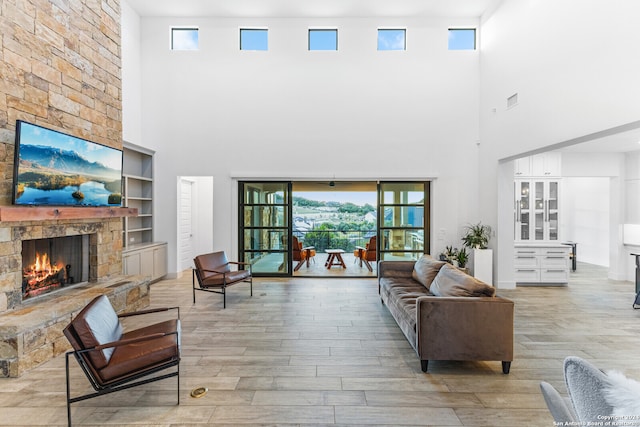 living room featuring light hardwood / wood-style floors, a high ceiling, a fireplace, and plenty of natural light