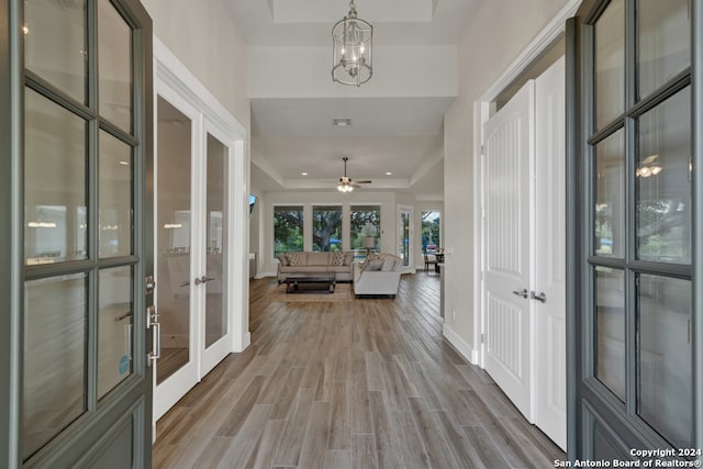 interior space featuring french doors, a tray ceiling, a chandelier, and hardwood / wood-style floors