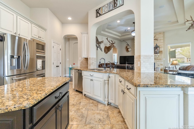 kitchen featuring light stone countertops, backsplash, kitchen peninsula, and white cabinetry