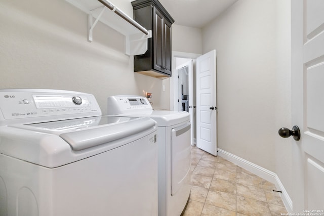 laundry area with cabinets, light tile patterned floors, and washing machine and dryer