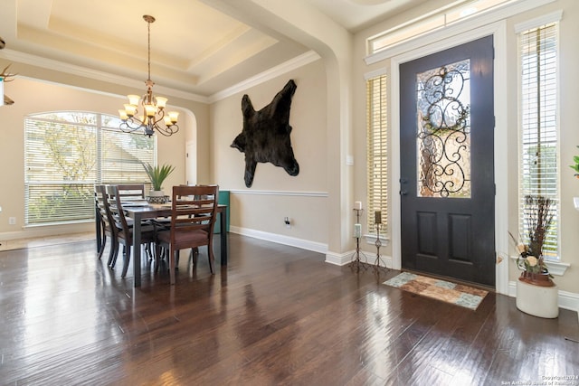 dining area with a raised ceiling, crown molding, and dark wood-type flooring