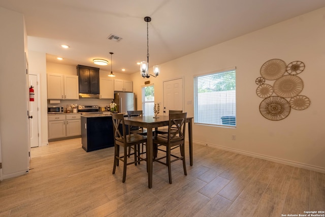 dining space with light wood-type flooring and a chandelier