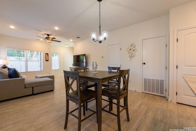 dining room with ceiling fan with notable chandelier and light hardwood / wood-style floors