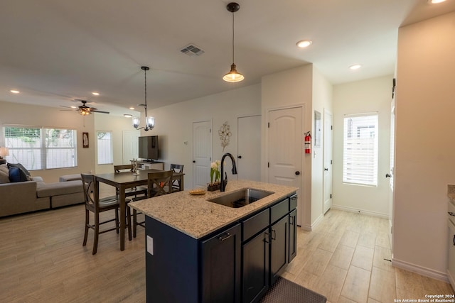 kitchen featuring an island with sink, light stone countertops, plenty of natural light, and sink