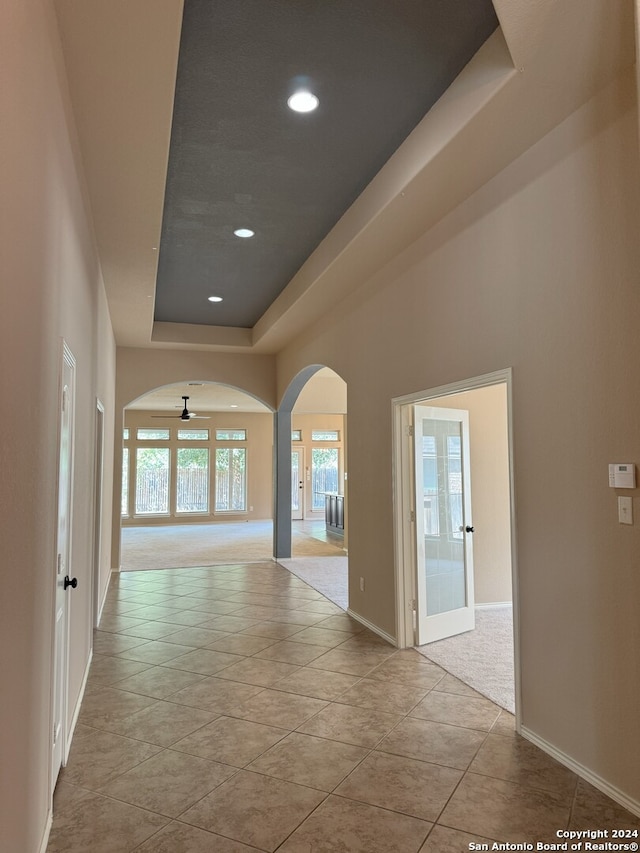 hallway featuring light tile patterned flooring and a raised ceiling