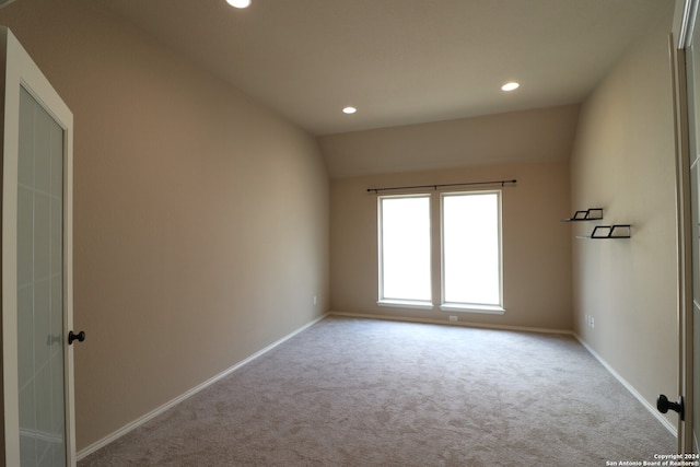 empty room with light carpet and vaulted ceiling