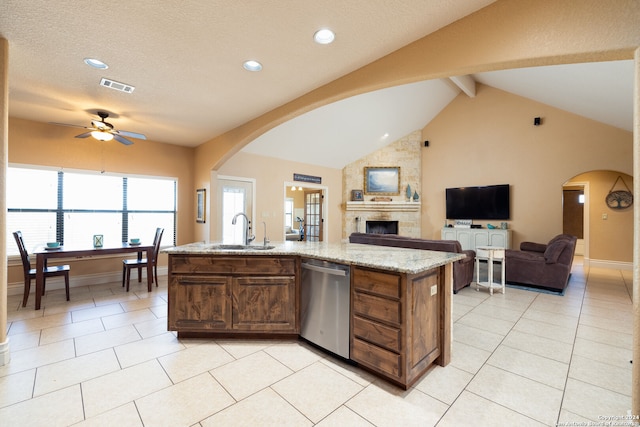 kitchen with a center island with sink, sink, stainless steel dishwasher, and light stone countertops